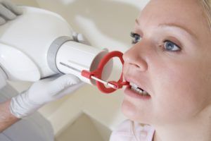 Woman biting down on a plastic piece during a dental xray