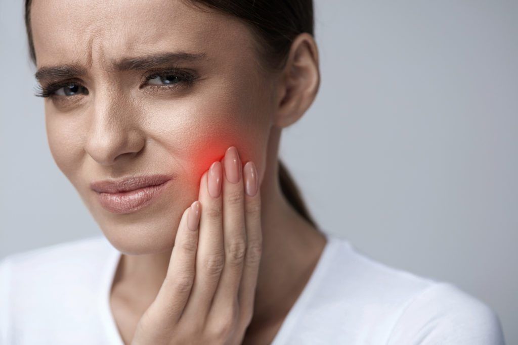 female holding her cheek in pain